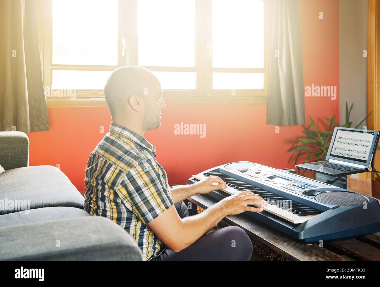 Man playing piano while taking online lessons Stock Photo