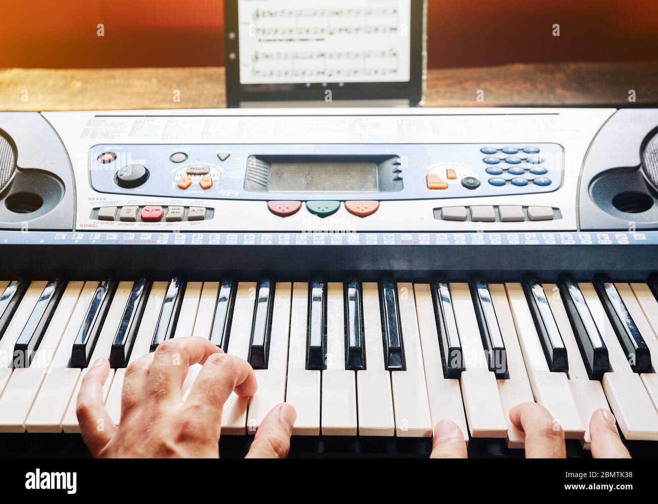 Man playing piano at home while using a tablet to read the scores Stock Photo