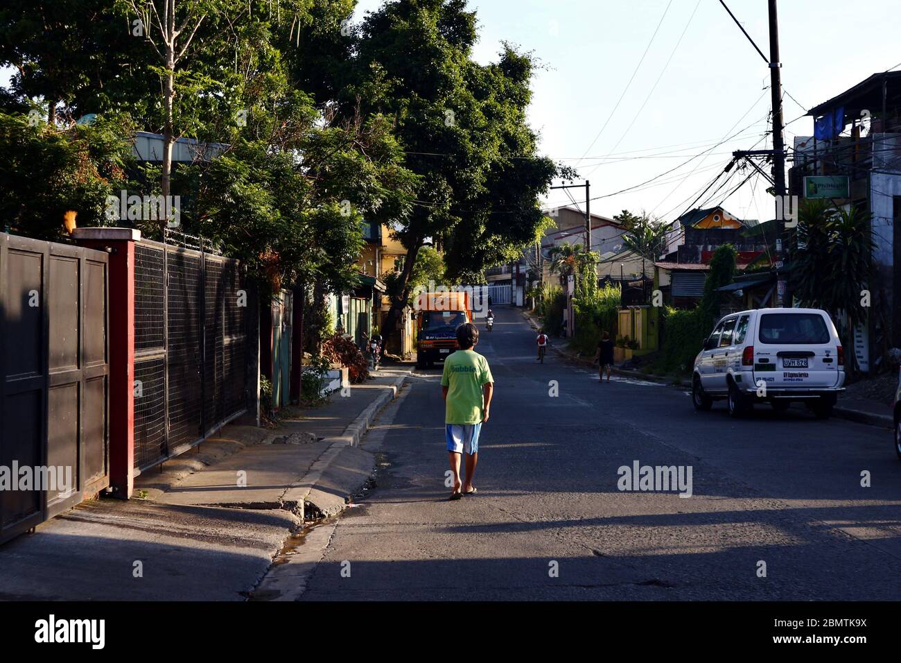 Antipolo City, Philippines - May 11, 2020: Man walking along an empty street with a beautiful ray of sun during sunrise. Stock Photo