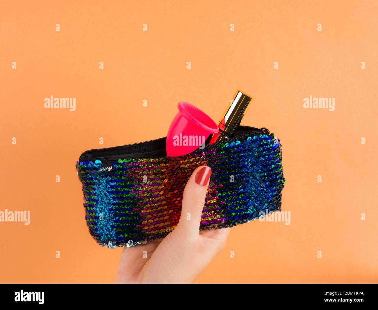 Pink menstrual cup in female sequin pochette bag Stock Photo
