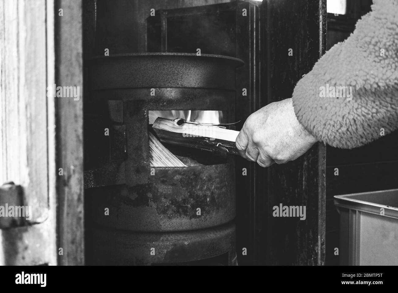 Stoking a wood stove in winter Stock Photo