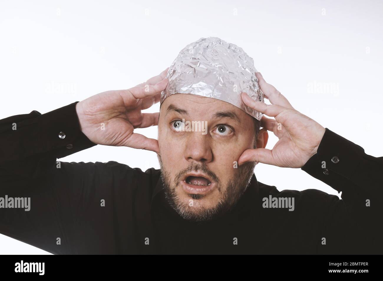 paranoid man wearing tin foil hat as protection against mind control and electromagnetic fields - conspiracy theaory Stock Photo