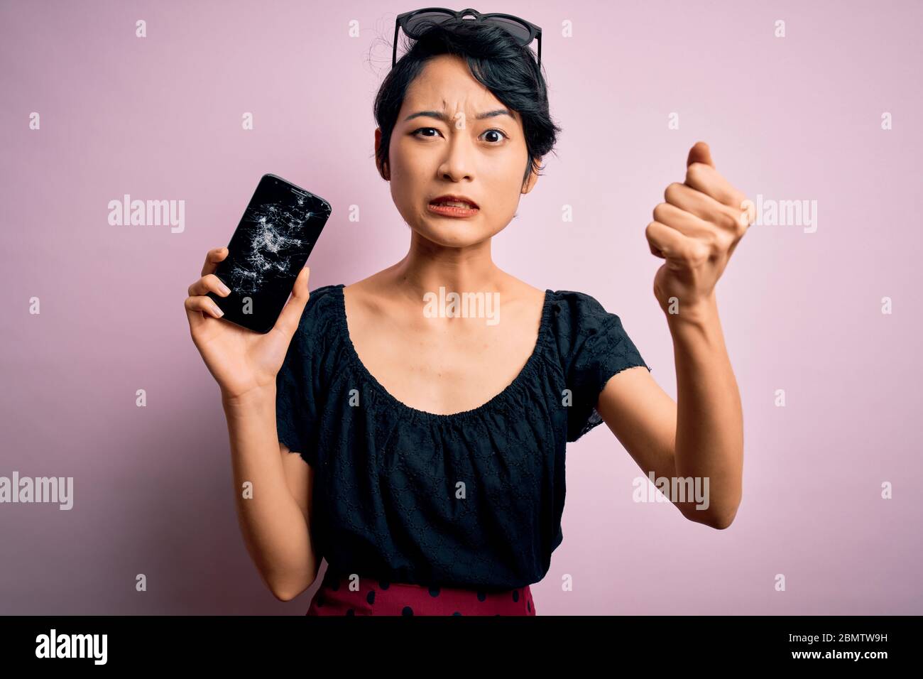 Young beautiful chinese woman holding broken smartphone showing craked  screen annoyed and frustrated shouting with anger, crazy and yelling with  raise Stock Photo - Alamy