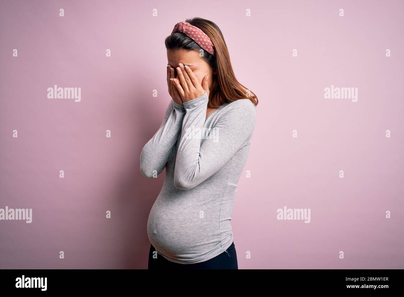 Young beautiful teenager girl pregnant expecting baby over isolated pink background rubbing eyes for fatigue and headache, sleepy and tired expression Stock Photo