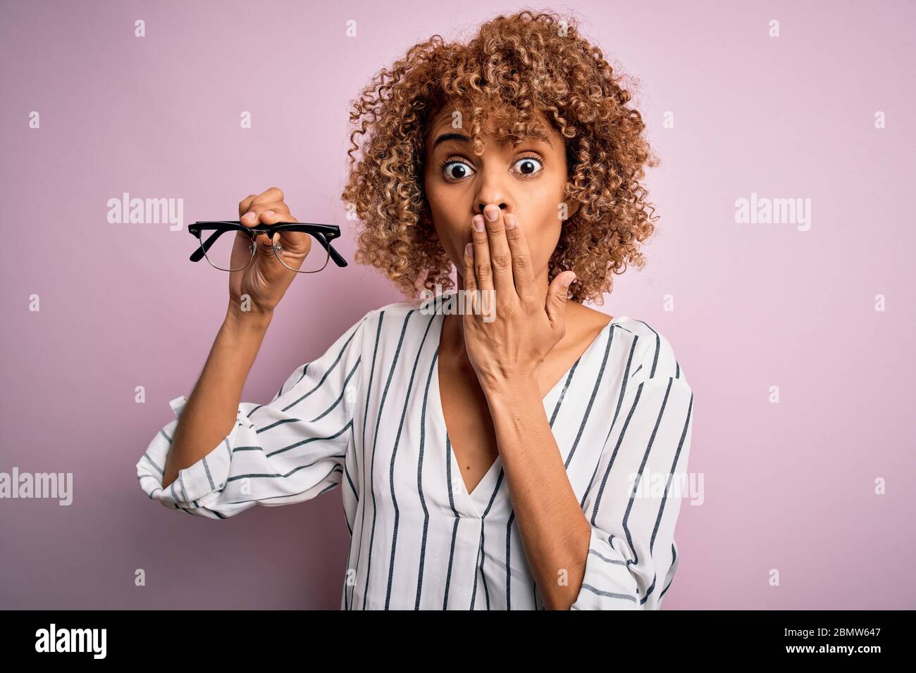 African american optical woman with curly hair holding glasses over ...