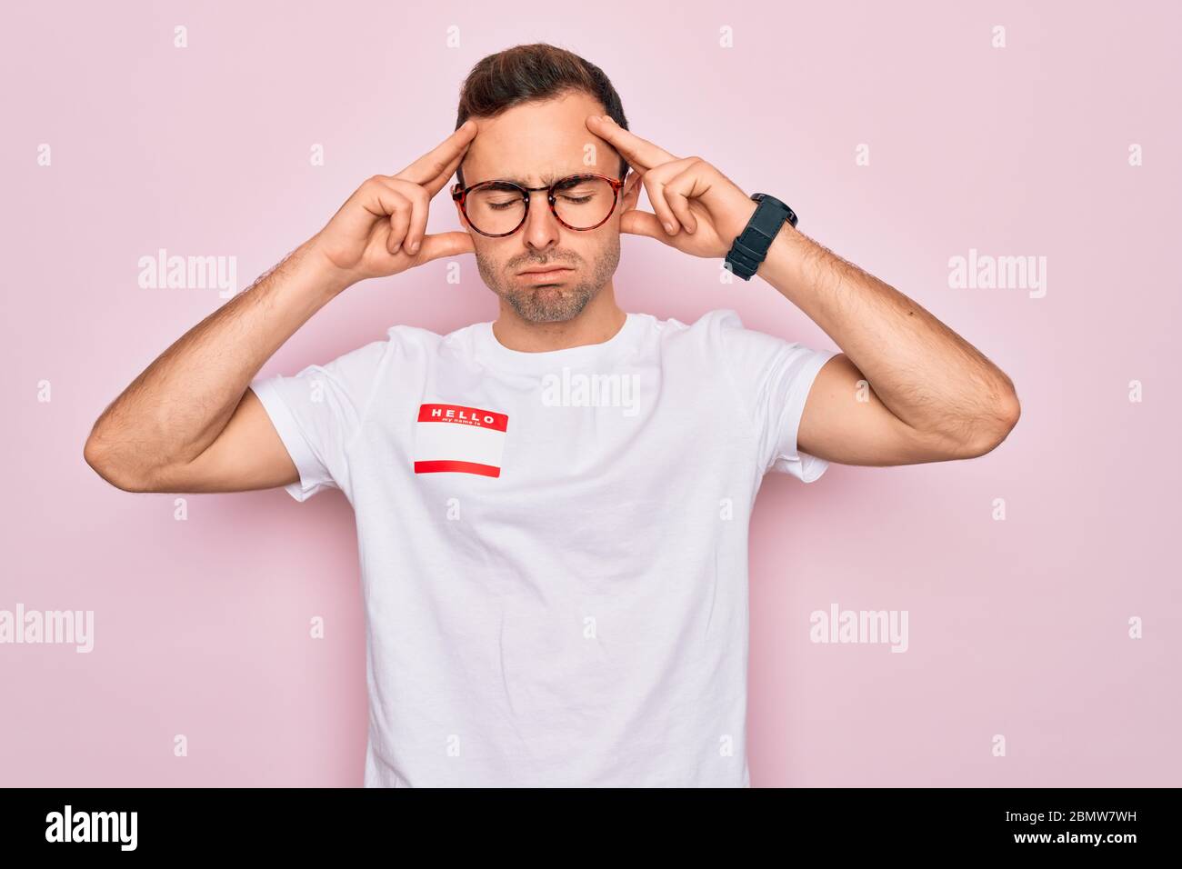 Handsome man with blue eyes wearing sticker with hello my name is ...