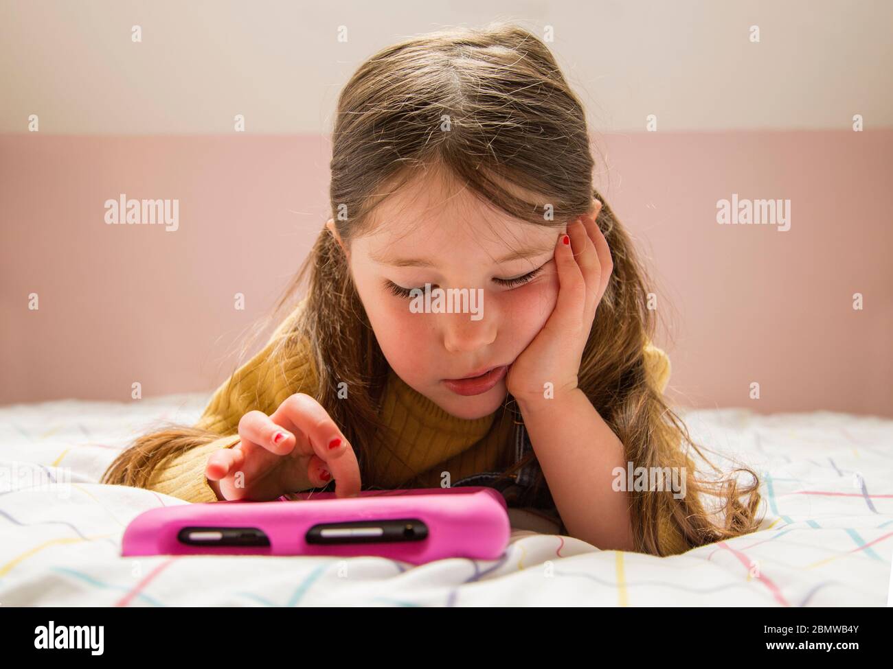 Young girl playing on a tablet looking bored Stock Photo