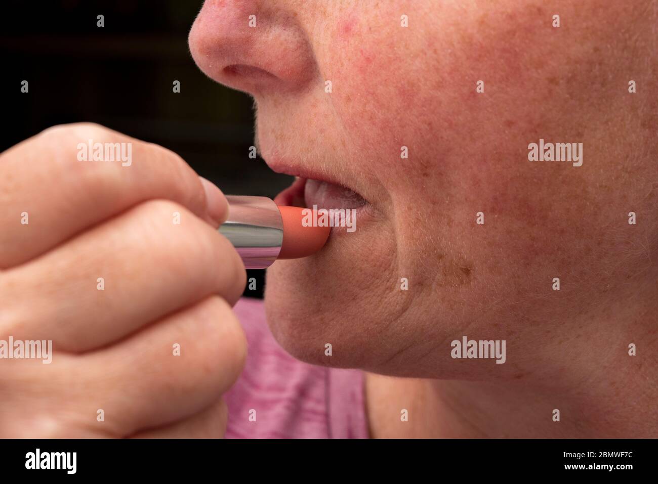 woman over 50 applying lipstick Stock Photo