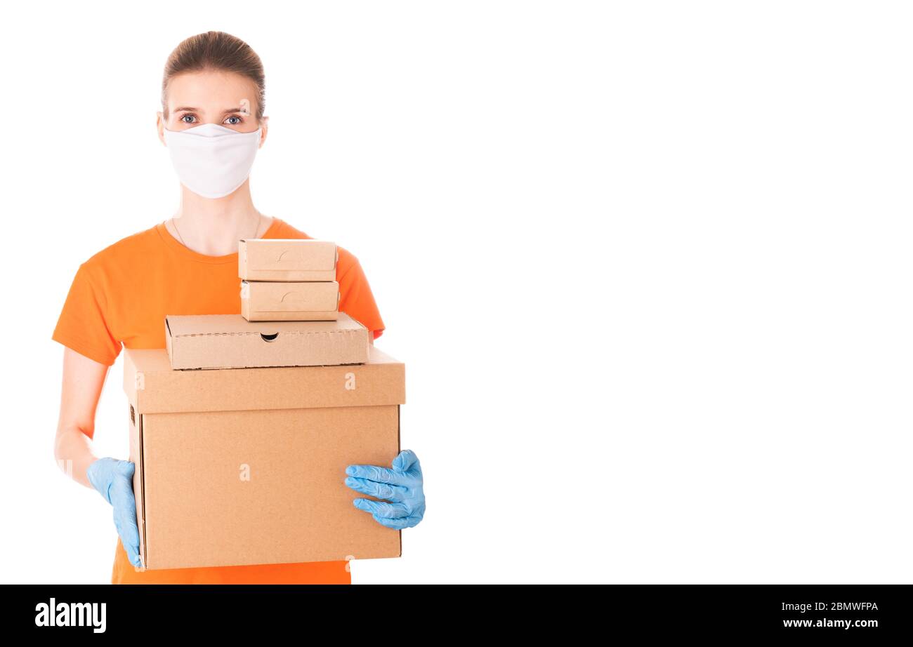 young girl in a mask and an orange t-shirt holds cardboard boxes for ...