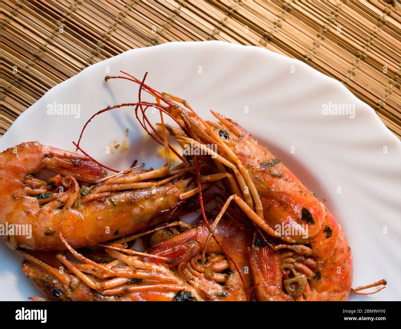 A fried lobster on a white plate, a straw lining under plate, garlic, close up Stock Photo