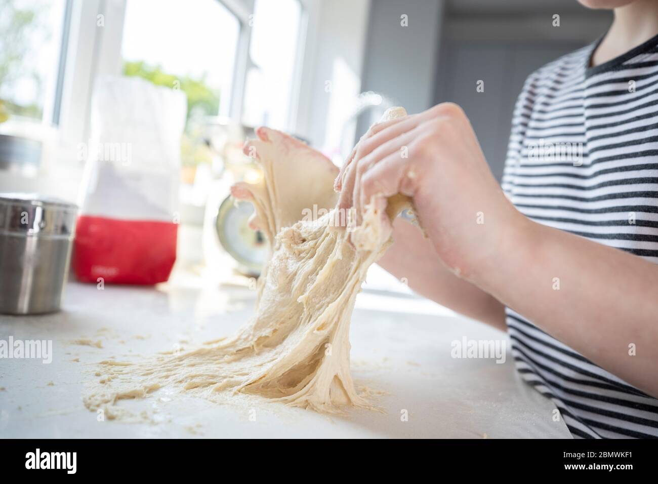 Close Up Of Portrait Of Girl With Messy Hands Having Fun In Kitchen Kneading Dough For Baking Stock Photo
