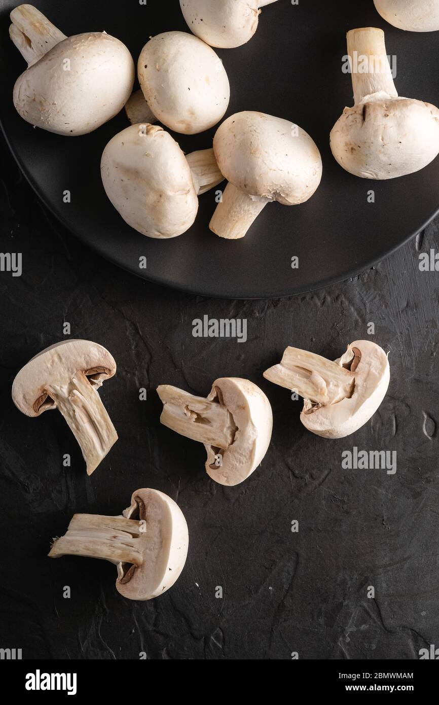 Top down view of dirty mushrooms in a black plastic container and a mushroom  cleaning brush on a textured surface Stock Photo