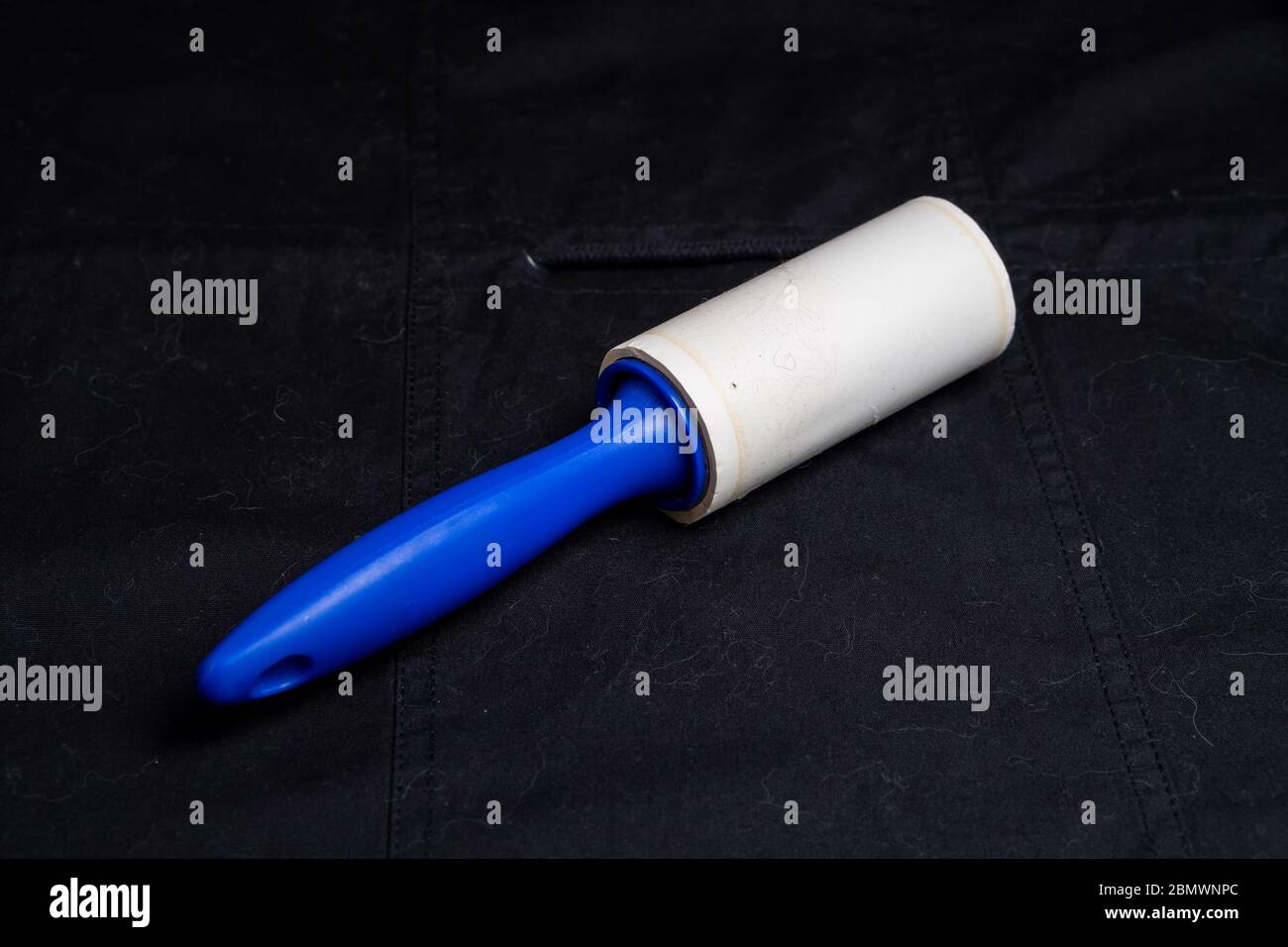 Adhesive roller for cleaning cloth on a black cloth Stock Photo