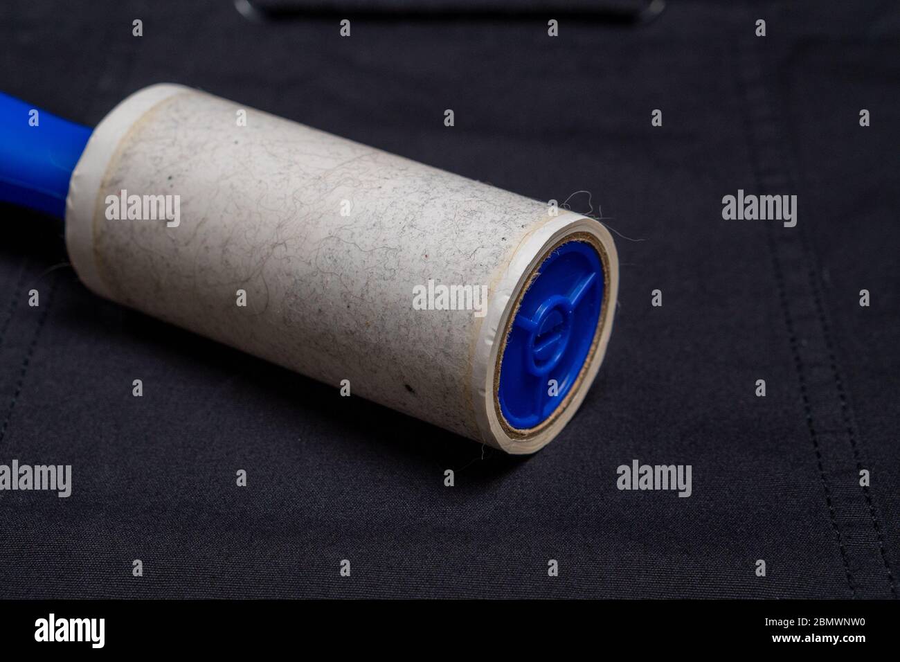 Adhesive roller for cleaning cloth on a black cloth, closeup Stock Photo