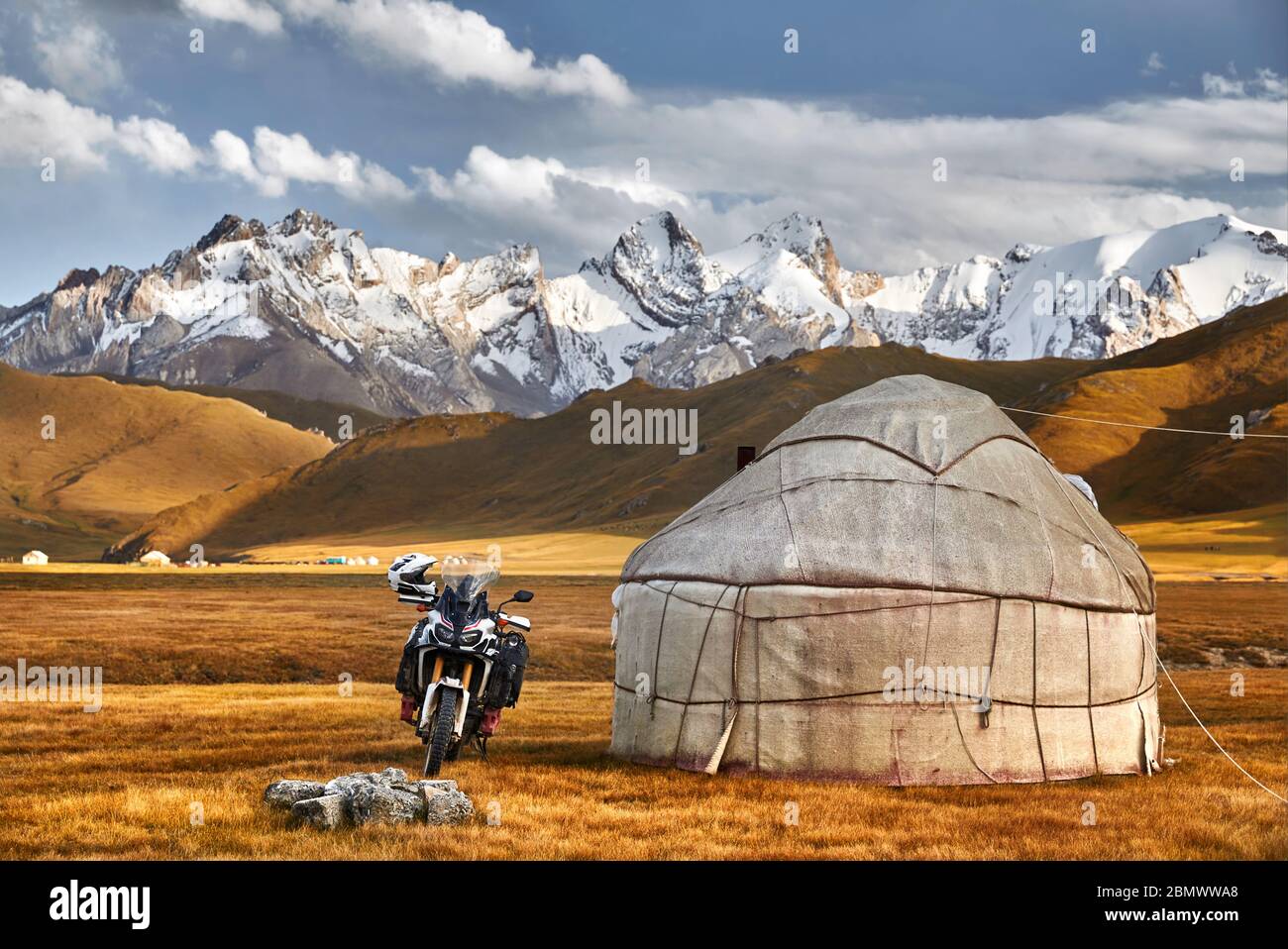 Yurt nomadic houses camp and motorcycle at mountain valley in Central Asia Stock Photo
