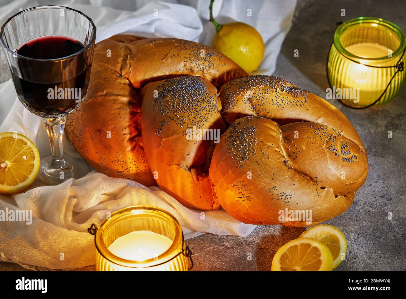 Shabbat challah with a white napkin, with candles, a glass of wine and rustic lemons. Shabbat Shalom Stock Photo