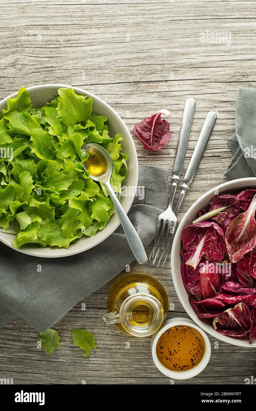 Healthy red and green lettuce salad meals on wooden table background. Eating fresh radicchio and young lettuce with dressing sauce Stock Photo