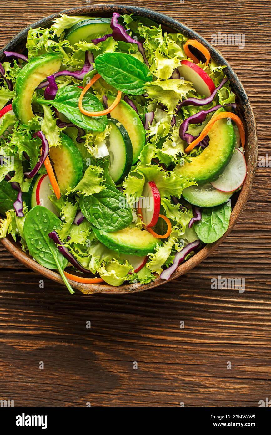 Green lettuce salad with fresh mixed vegetables on wooden table background Stock Photo