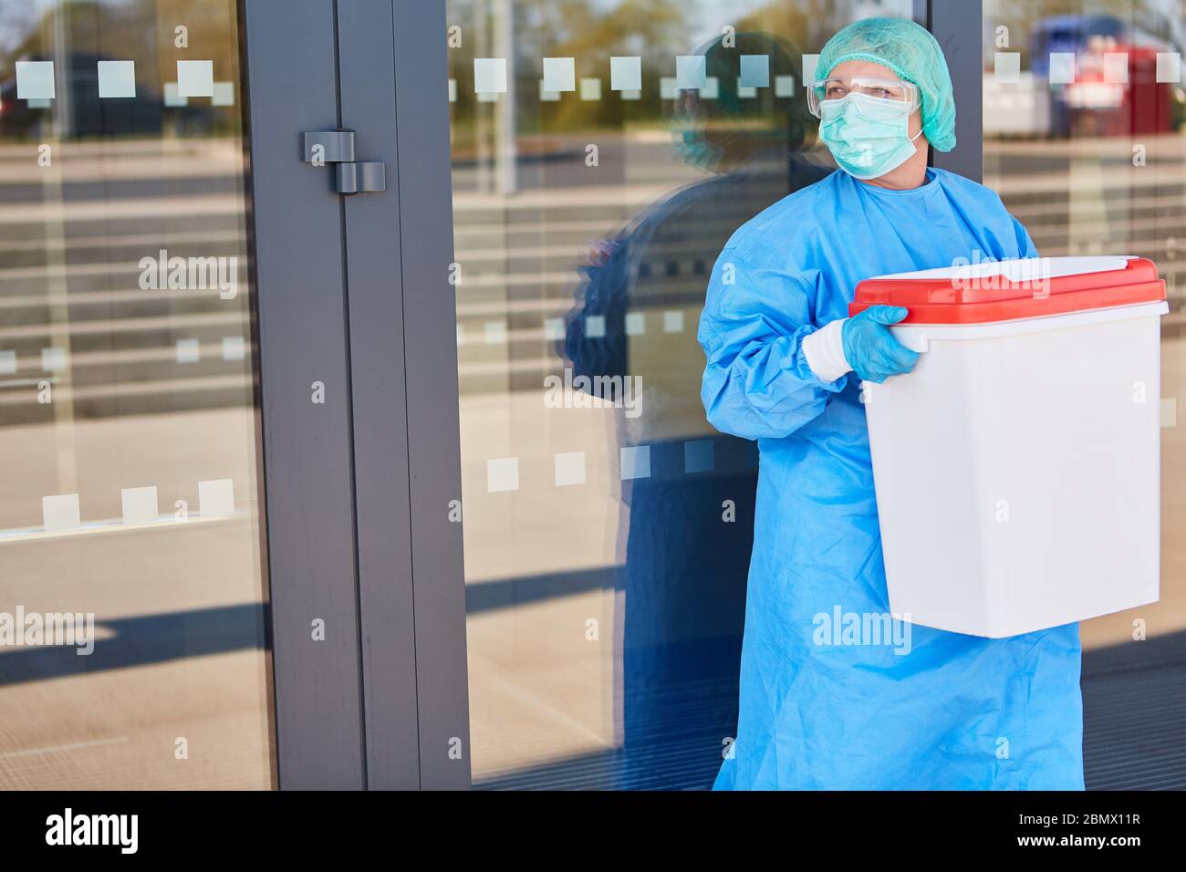 Doctor or surgeon with organ transport after organ donation for surgery in front of the clinic in protective clothing Stock Photo