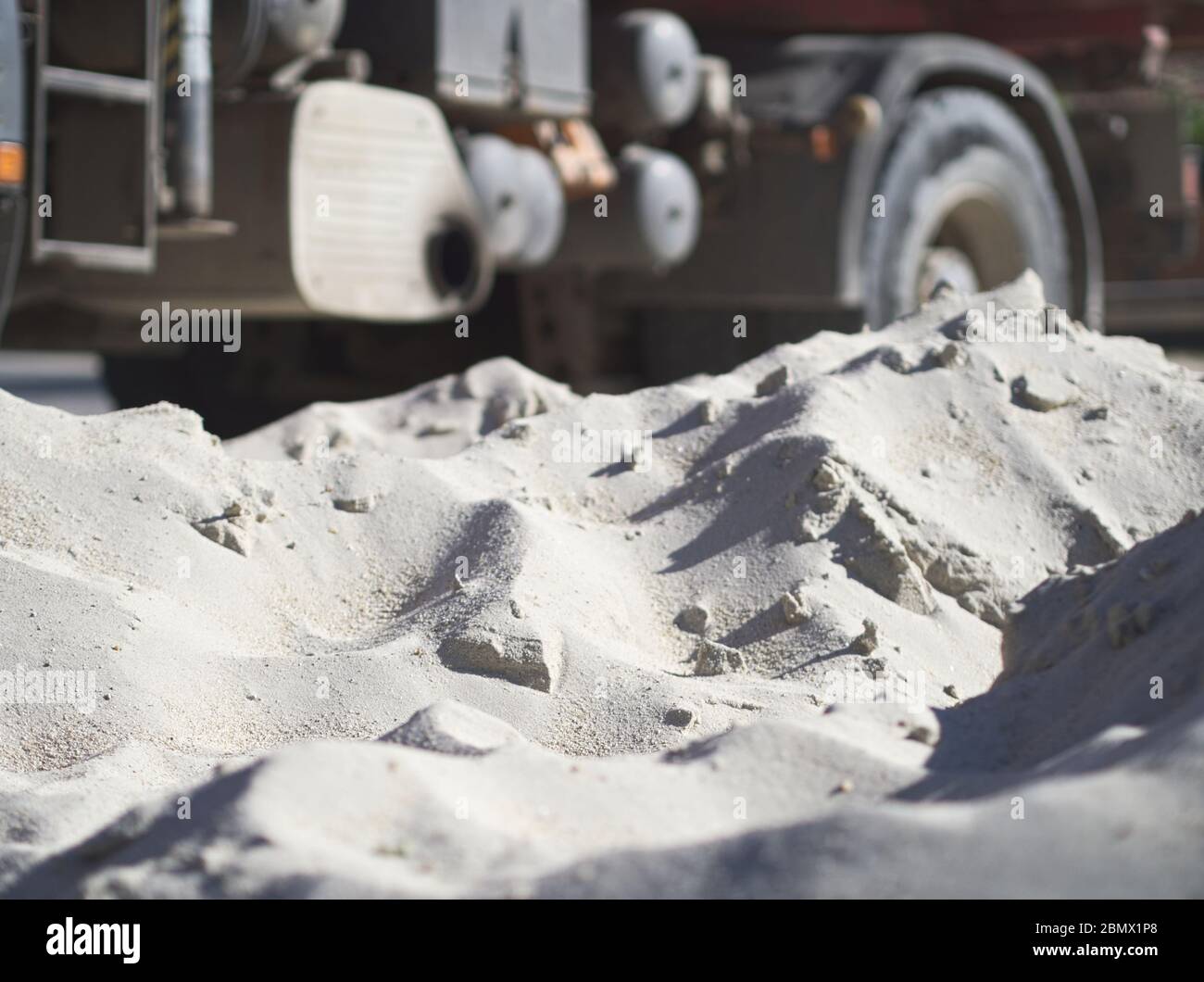 Piled up Fine White Sand Construction Material with Truck in Background Stock Photo