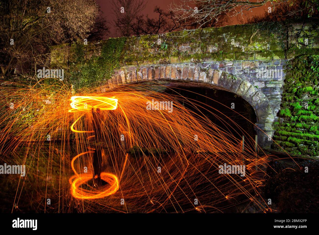afire spinning with steel wool at an old disused railway bridge Stock Photo