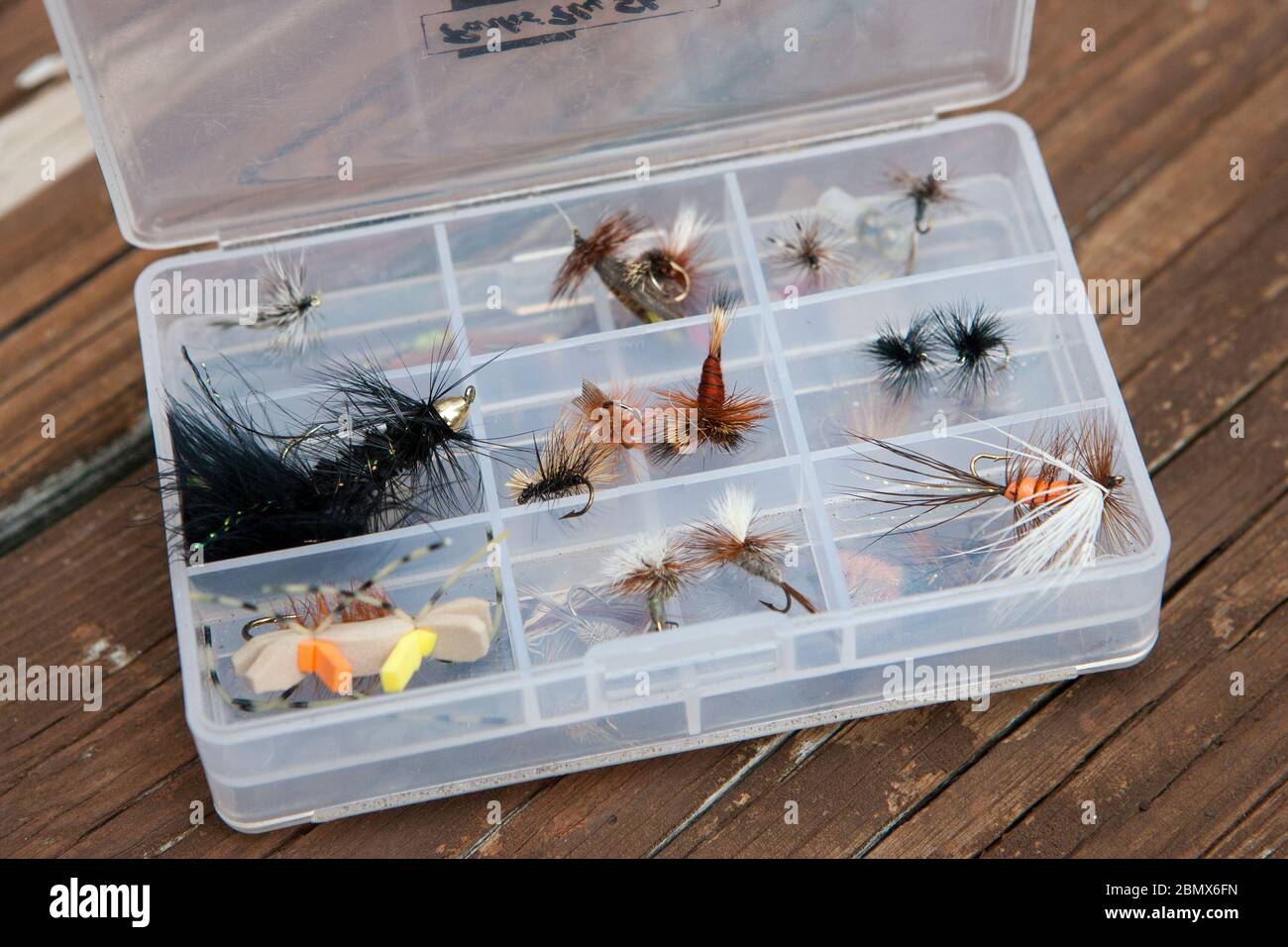 https://c8.alamy.com/comp/2BMX6FN/a-small-tackle-box-filled-with-fly-fishing-lures-stands-open-on-a-wooden-porch-in-the-catskills-new-york-usa-2BMX6FN.jpg