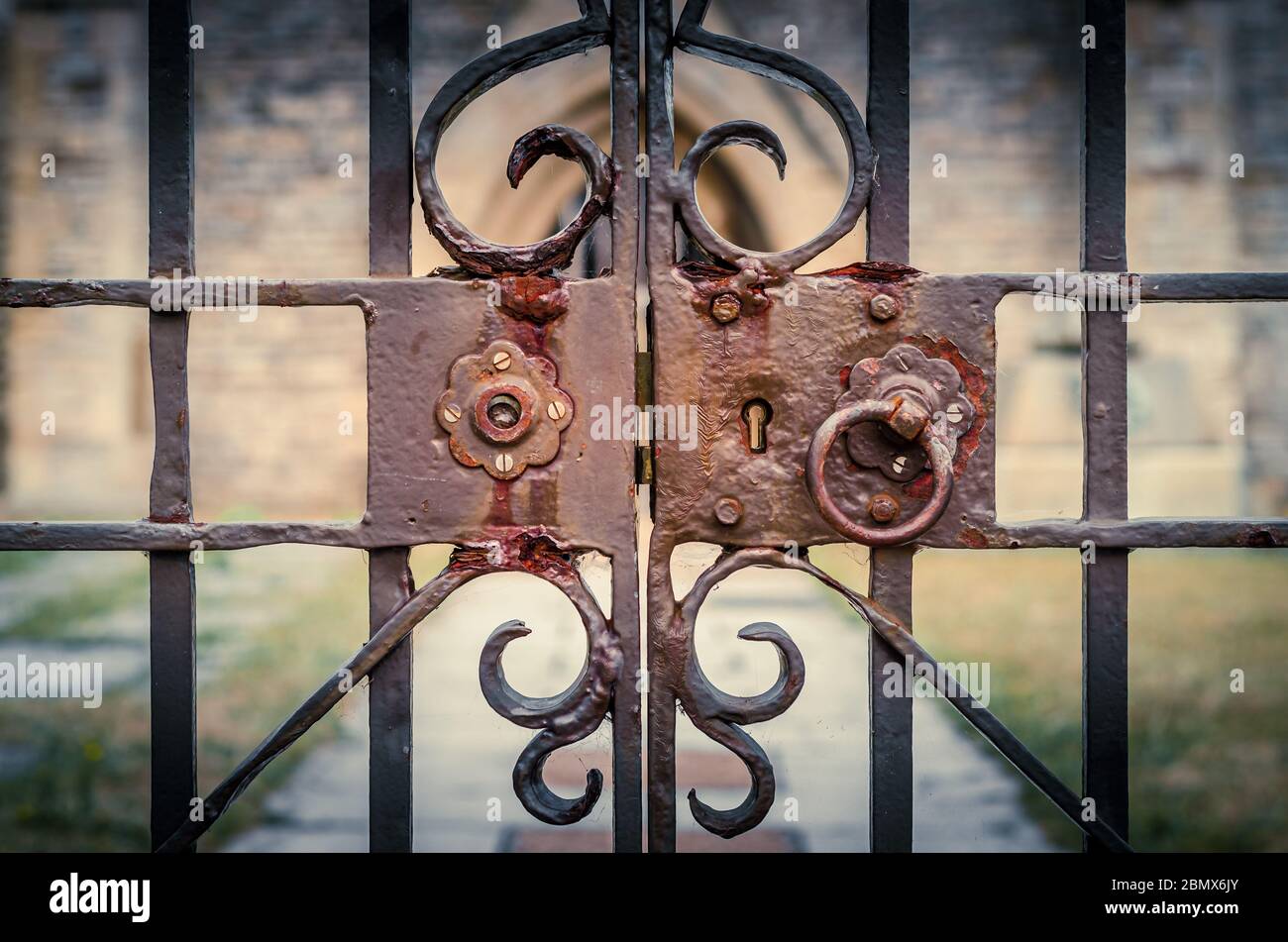 Old and rusty lock on ornate, locked iron gates of a church Stock Photo