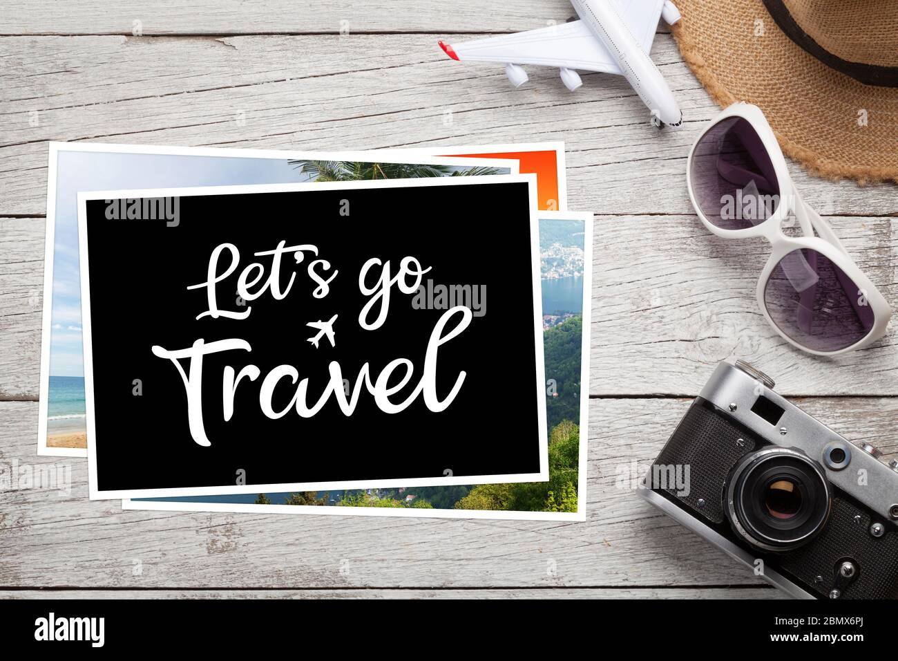 Travel concept with vacation photos, airplane toy, camera and sunglasses on wooden table. Top view flat lay with copy space Stock Photo