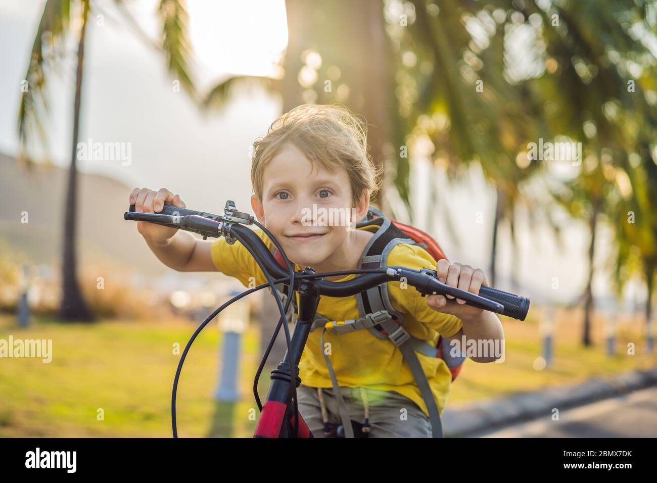 Kid Backpack Rider Active school kid boy riding a bike with backpack on sunny day. Happy ...