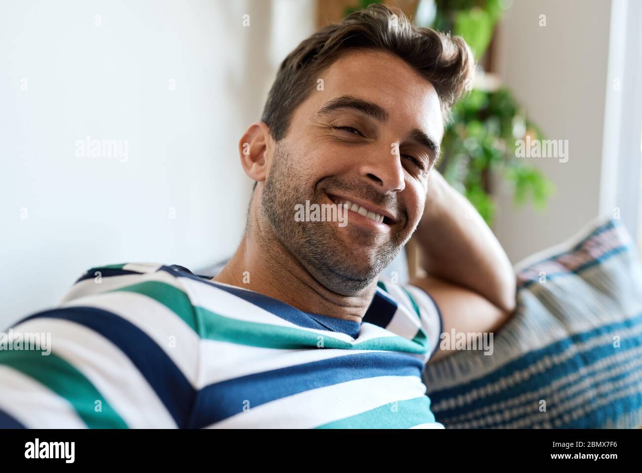 Smiling young man relaxing on his living room sofa Stock Photo