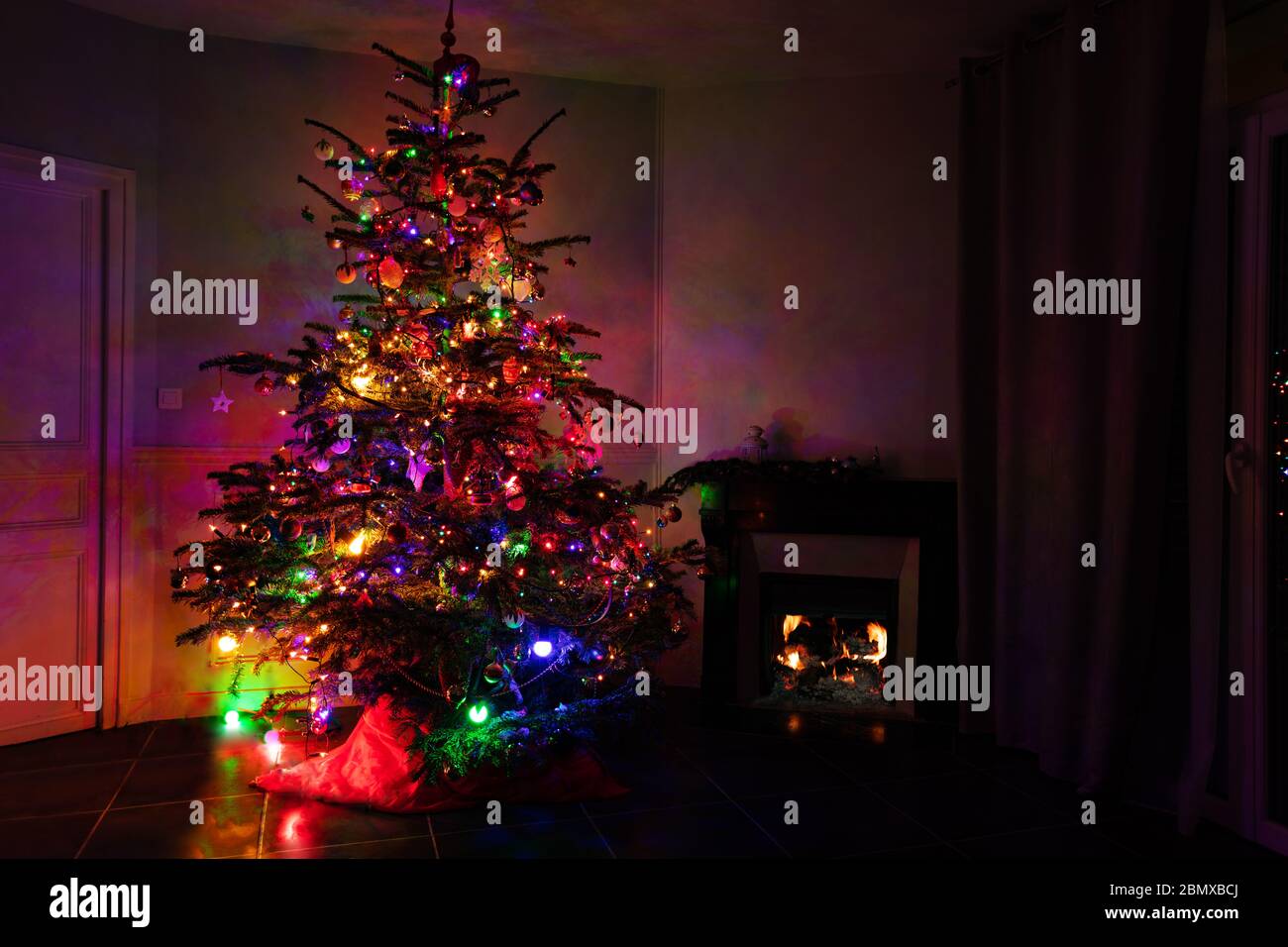 Illuminated Christmas tree in different color lights at night near