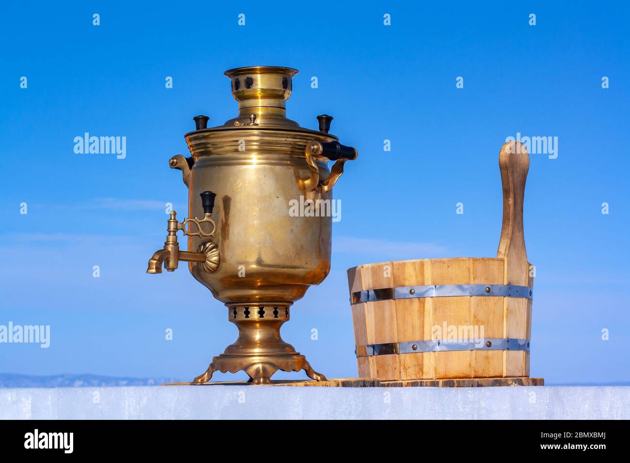 A brilliant samovar stands on an ice plate against a snow