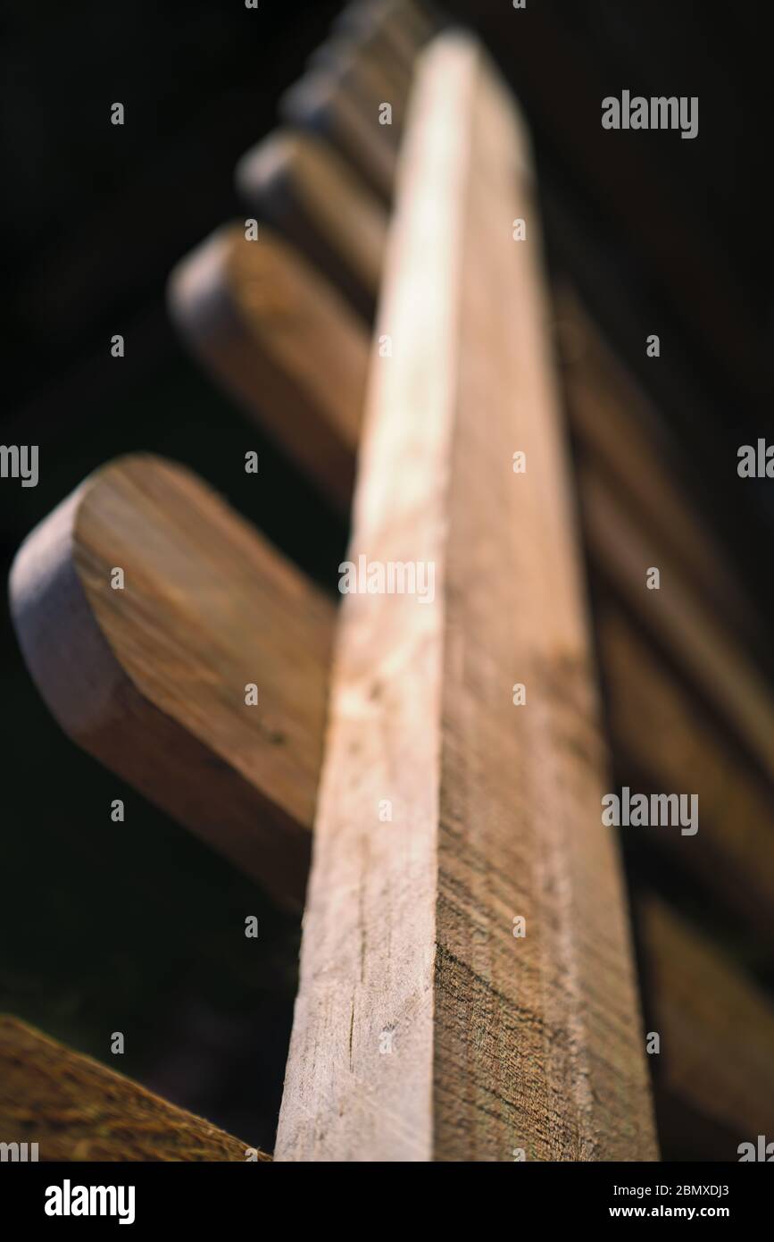 Top detail of a brown wood picket fence, with rounded tops to the posts in sunlight. Stock Photo