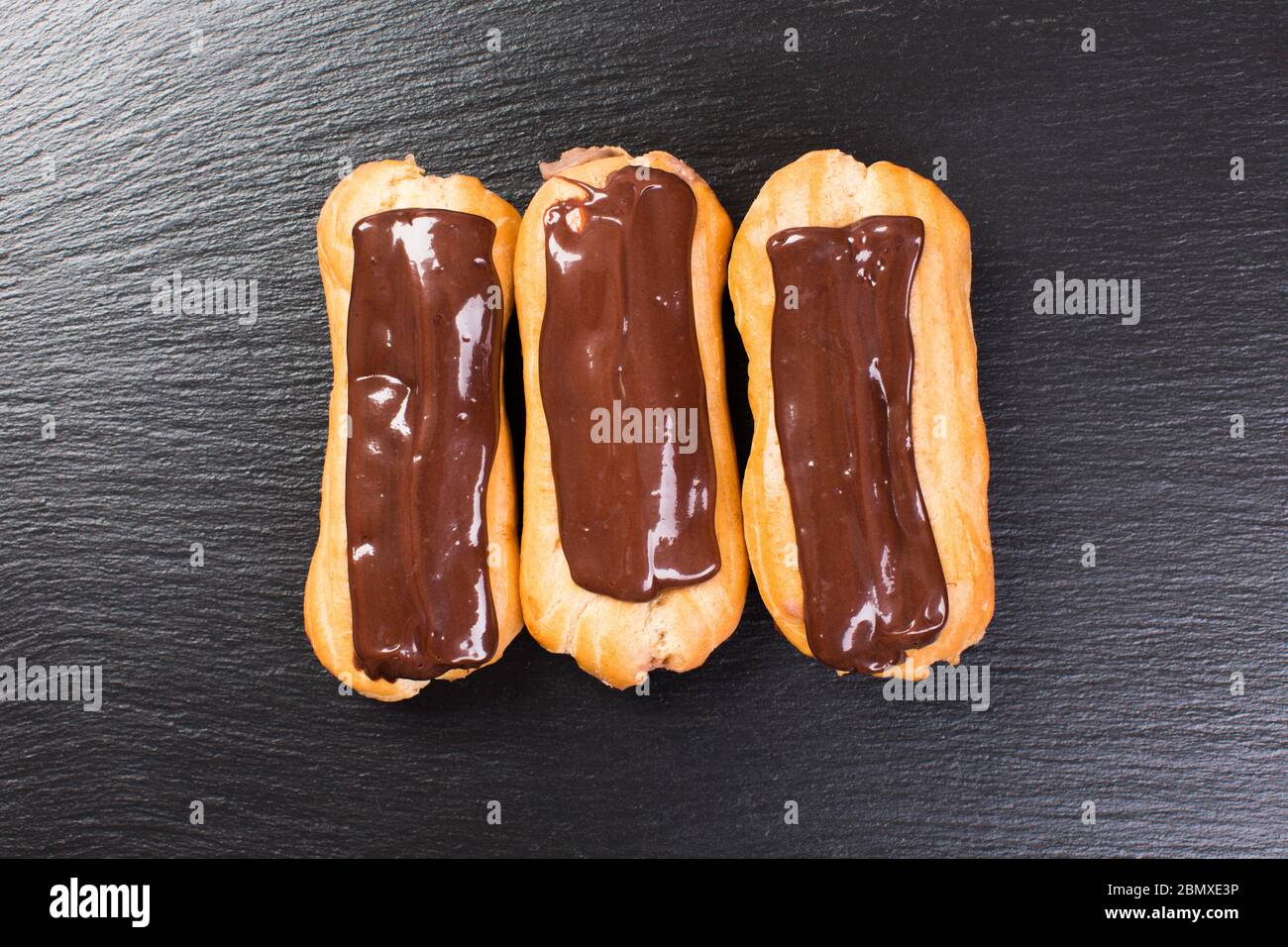 Delicious chocolate eclairs on a black table. Stock Photo