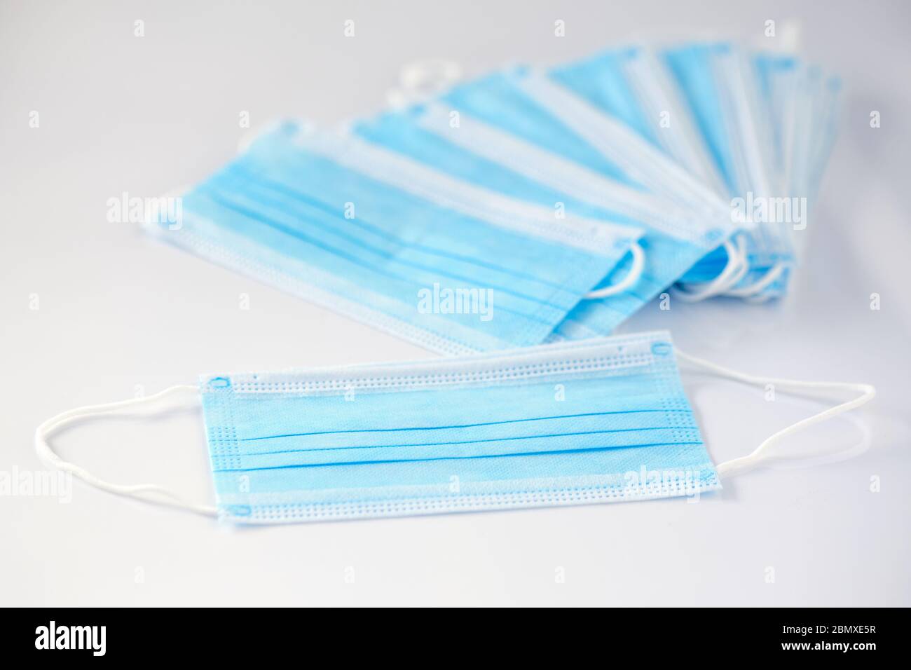 A stack of new unused disposable face masks lying on white background. Seen in Germany in May during corona crisis. Stock Photo