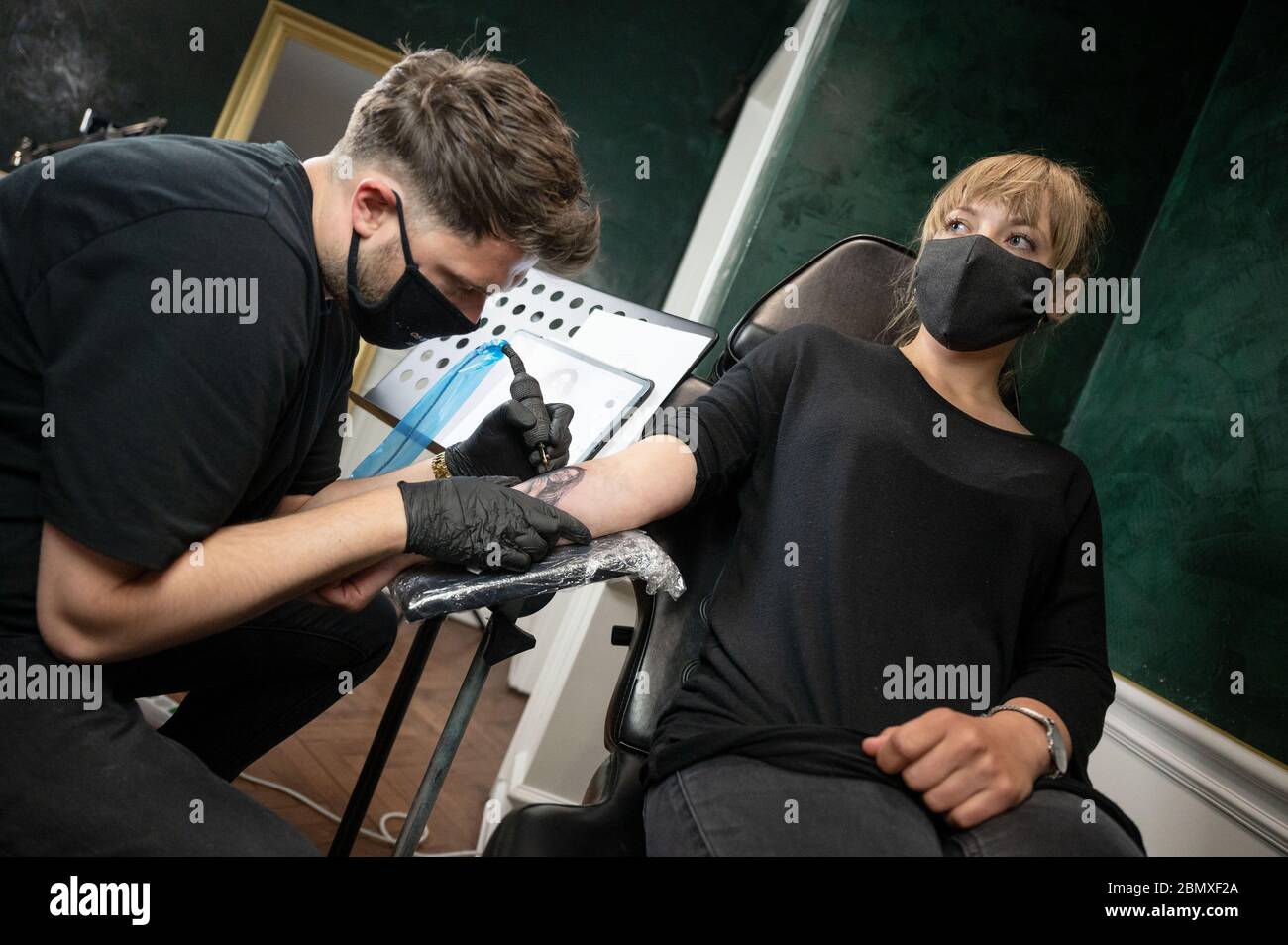 Stuttgart, Germany. 11th May, 2020. An employee of the tattoo studio 'Mommy I'm Sorry' tattoos a customer on her forearm. From 11 May onwards, relaxed corona rules apply in Baden-Württemberg. Among other things, tattoo studios are open again under certain conditions. Credit: Marijan Murat/dpa - ATTENTION: For editorial use only in connection with reporting on the relaxation of requirements to contain the Corona pandemic and only with full mention of the above credit/dpa/Alamy Live News Stock Photo