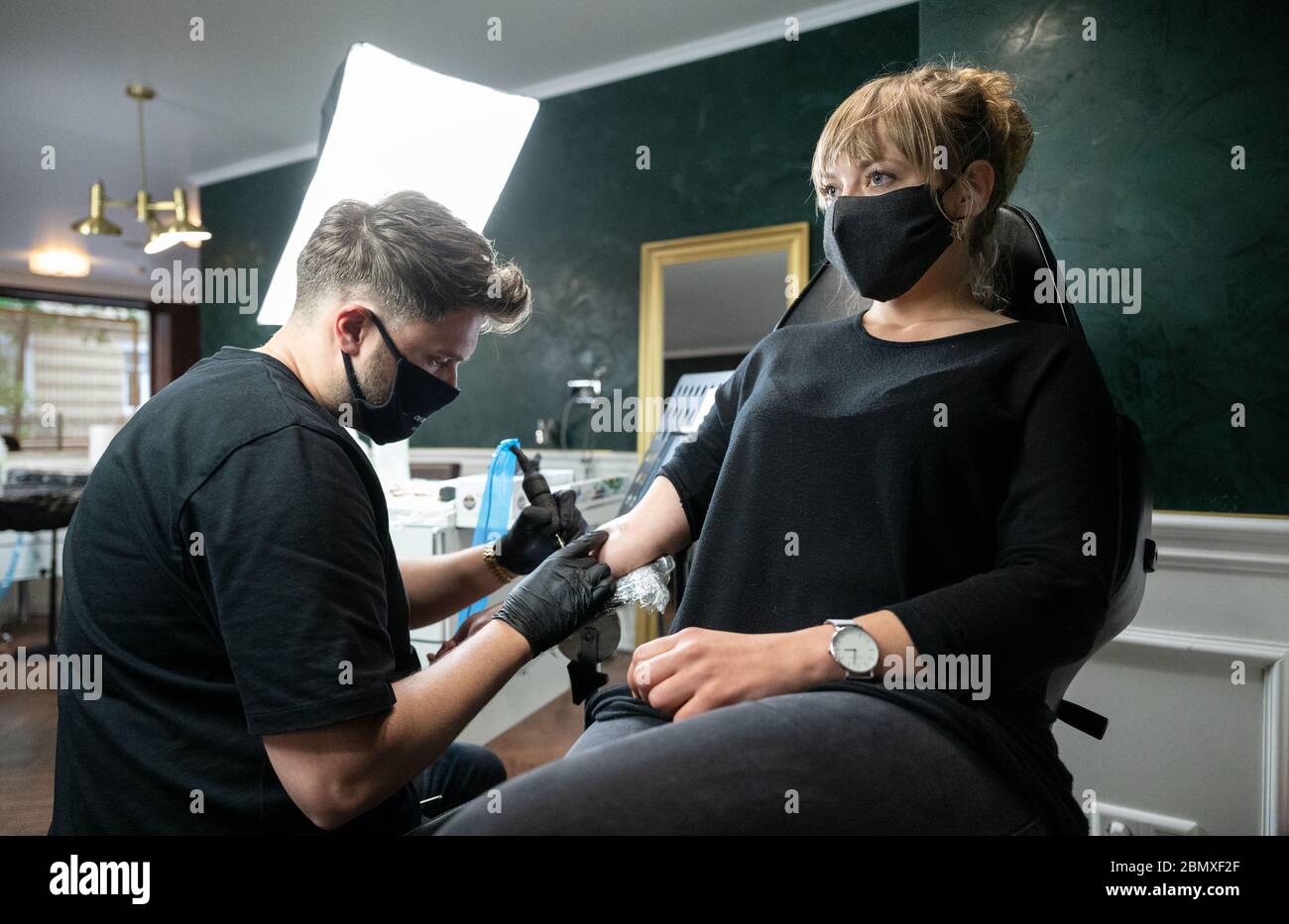 Stuttgart, Germany. 11th May, 2020. An employee of the tattoo studio 'Mommy I'm Sorry' tattoos a customer on her forearm. From 11 May onwards, relaxed corona rules apply in Baden-Württemberg. Among other things, tattoo studios are open again under certain conditions. Credit: Marijan Murat/dpa - ATTENTION: For editorial use only in connection with reporting on the relaxation of requirements to contain the Corona pandemic and only with full mention of the above credit/dpa/Alamy Live News Stock Photo