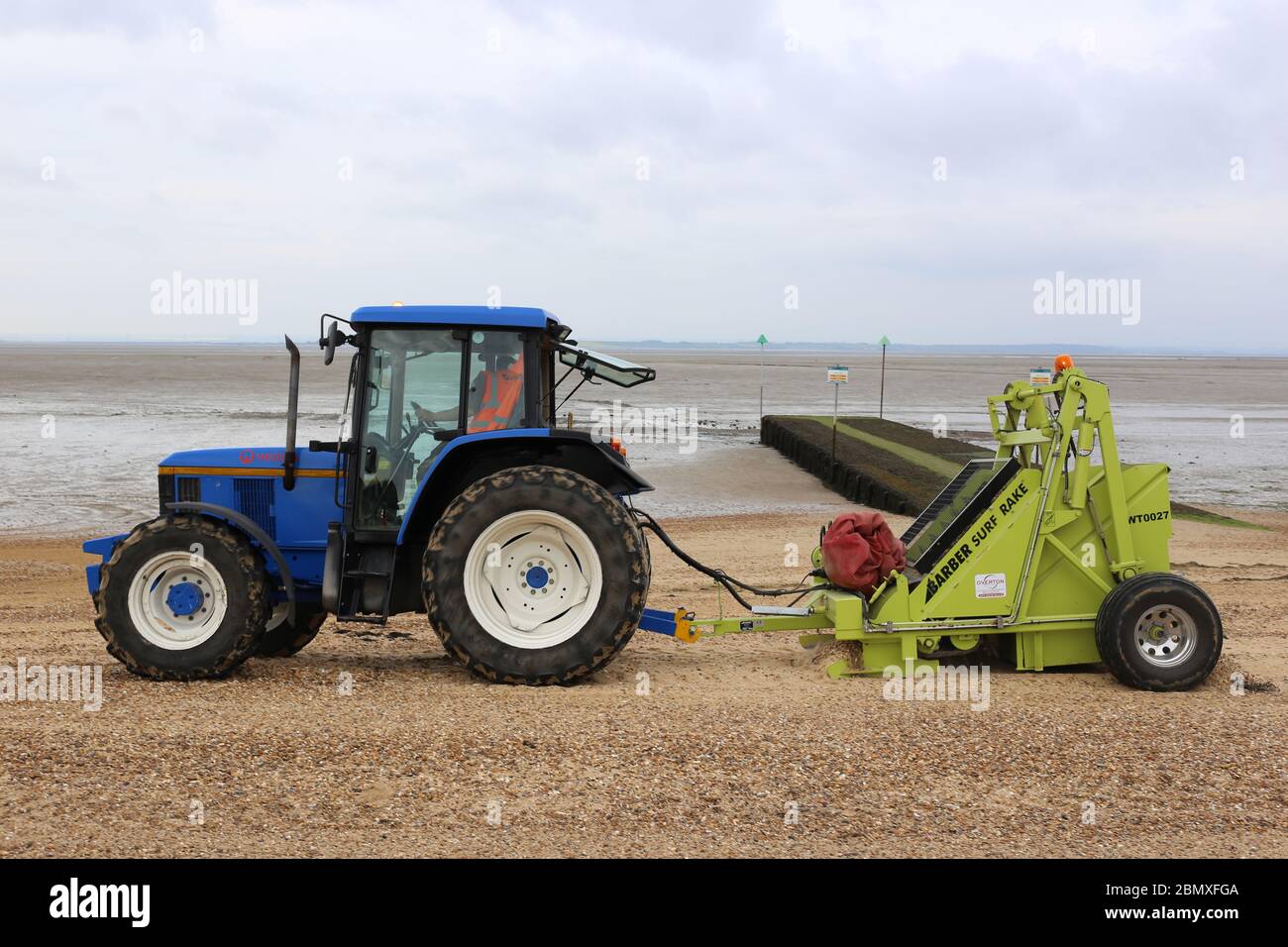 A tractor towing a “Surf Rake” attachment, cleaning the beach, at
