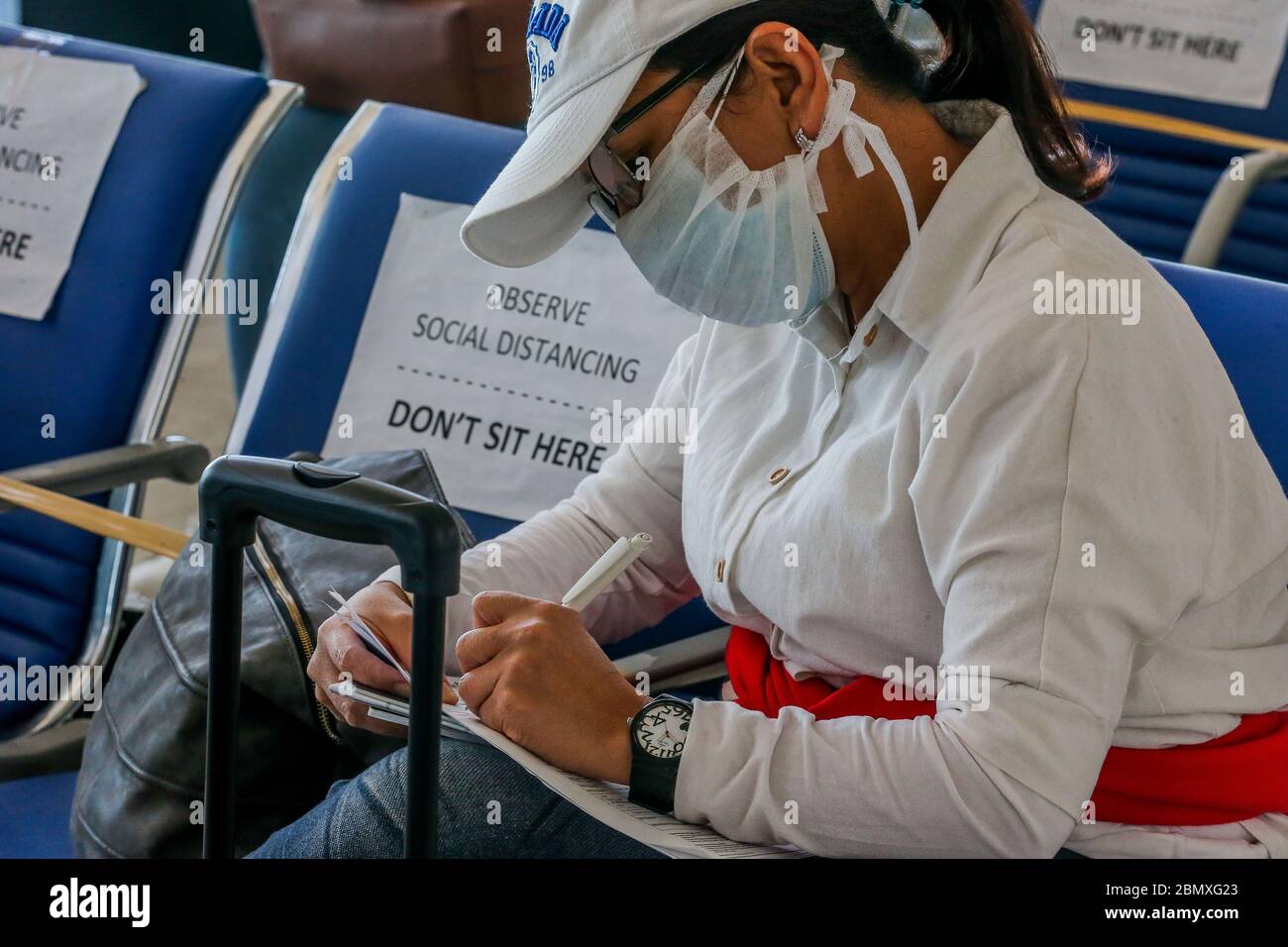 Manila. 11th May, 2020. A Filipino returning from London fills out a form after arriving at the Manila Ninoy Aquino International Airport in the Philippines, May 11, 2020. All foreigners and Filipinos arriving in the Philippines need to undergo testing for the COVID-19 and quarantine to stem the spread of the virus, Presidential spokesperson Harry Roque said on Monday. Credit: Rouelle Umali/Xinhua/Alamy Live News Stock Photo
