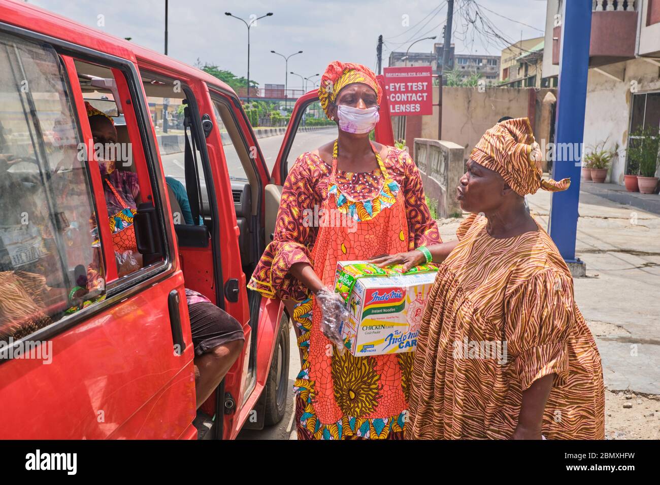 A woman receives a carton of noodles from a private relief worker during Covid-19 lockdown in Lagos, Nigeria. Stock Photo