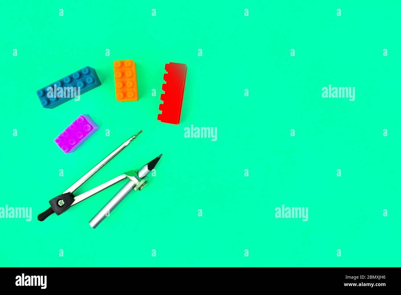 Building blocks and a silver color wood pencil attached to a pencil compass placed on a blue paper background Stock Photo