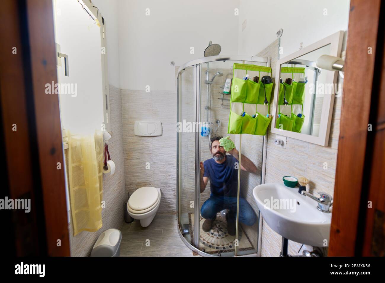 man cleaning the bathtub glass during coronavirus quarantine Stock Photo