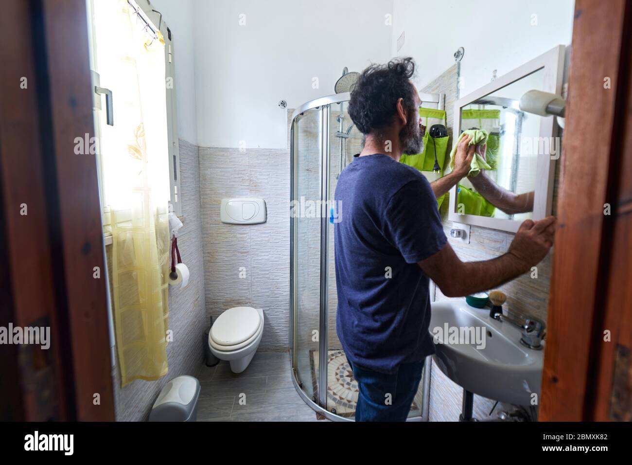 man cleaning the bathroom mirror during coronavirus quarantine Stock Photo