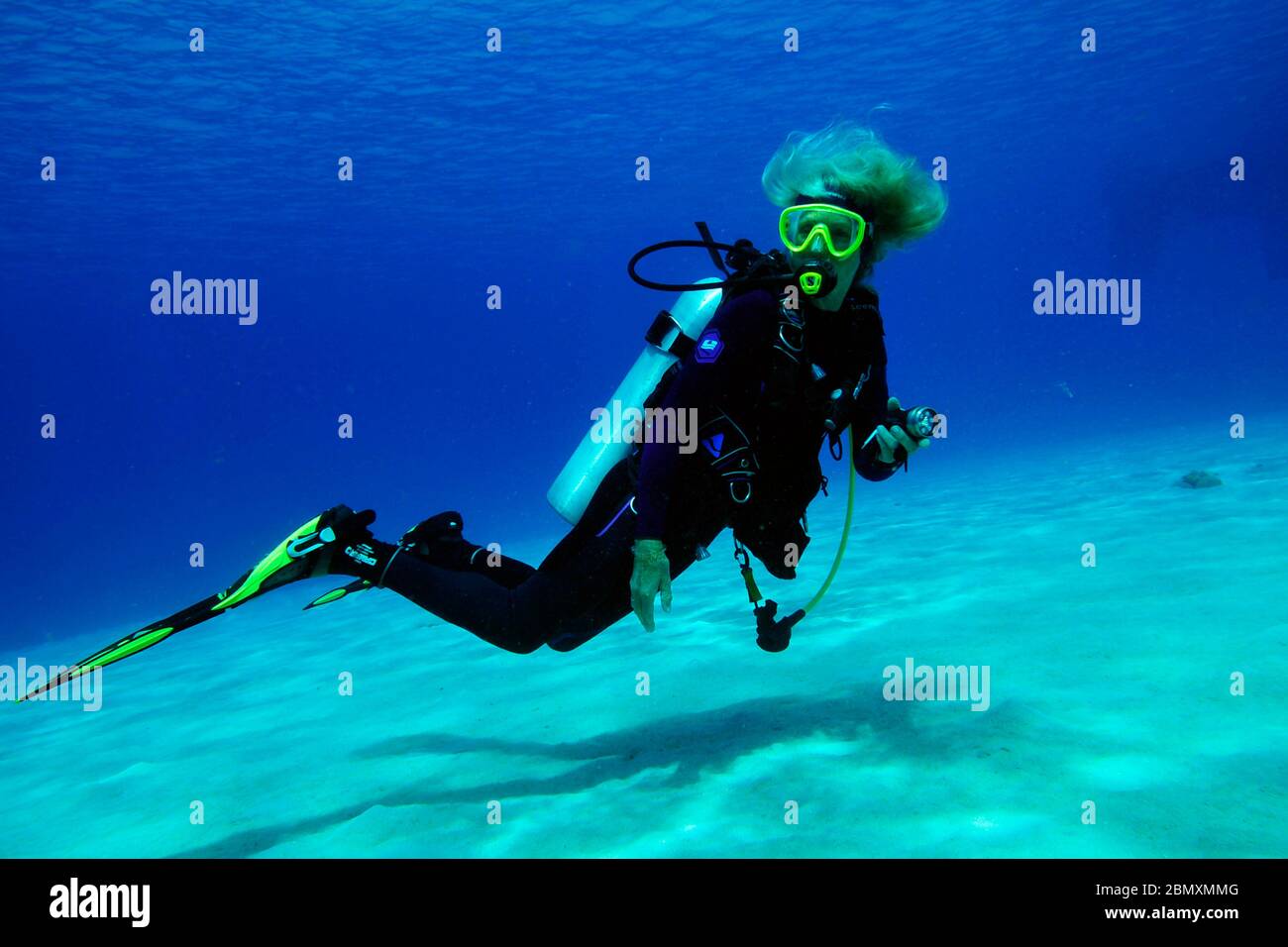 Lady diver full equipped over the sandy ground of the caribbean sea, Bonaire island. Stock Photo