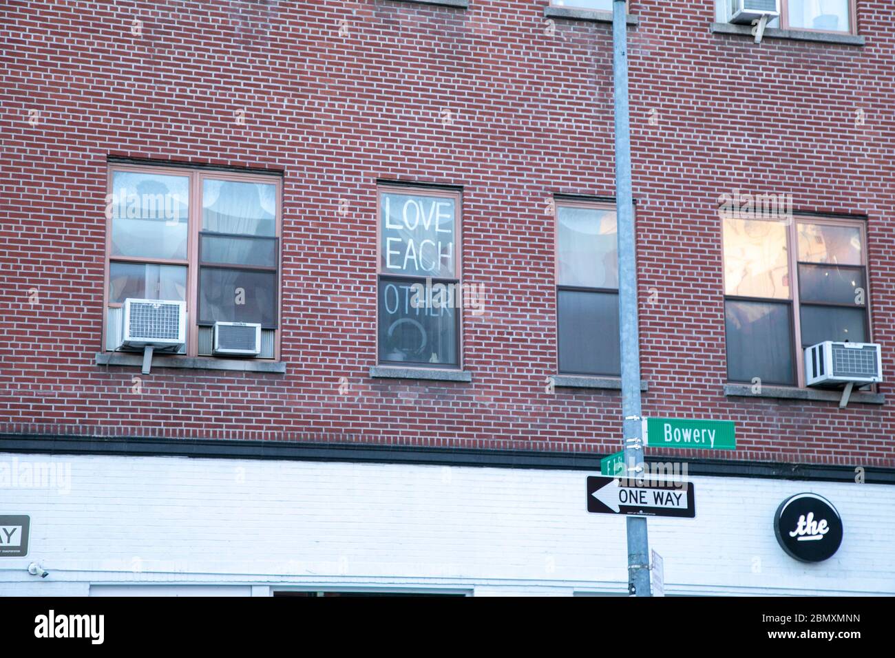 A sign in window saying 'love each other' on the Bowery in New York City. Stock Photo