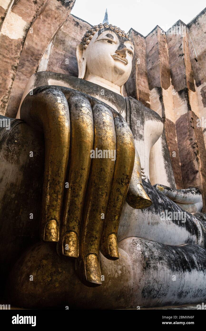 Low angle shot of a giant buddha statue carved out directly from the rocks. Extremely long fingers are in the foreground, Sukhothai, Thailand Stock Photo