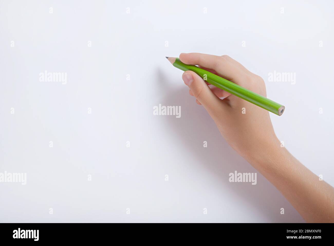 The child's hand holding a pencil against a white sheet of paper Stock Photo