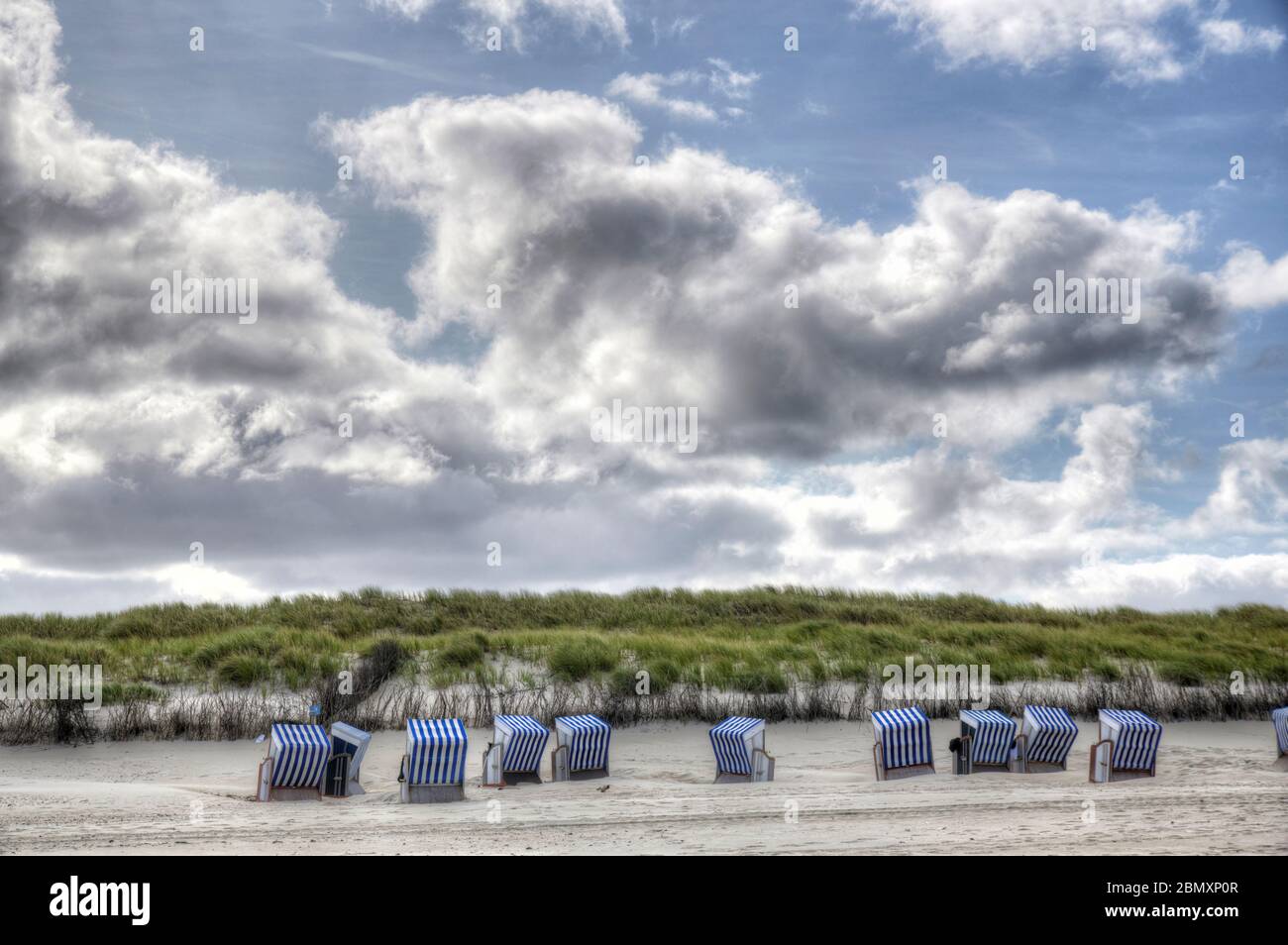 Strandkoerbe am Strand von Norderney auf der Hoehe der 'Weissen Duene' mit dramatischem Himmel Stock Photo