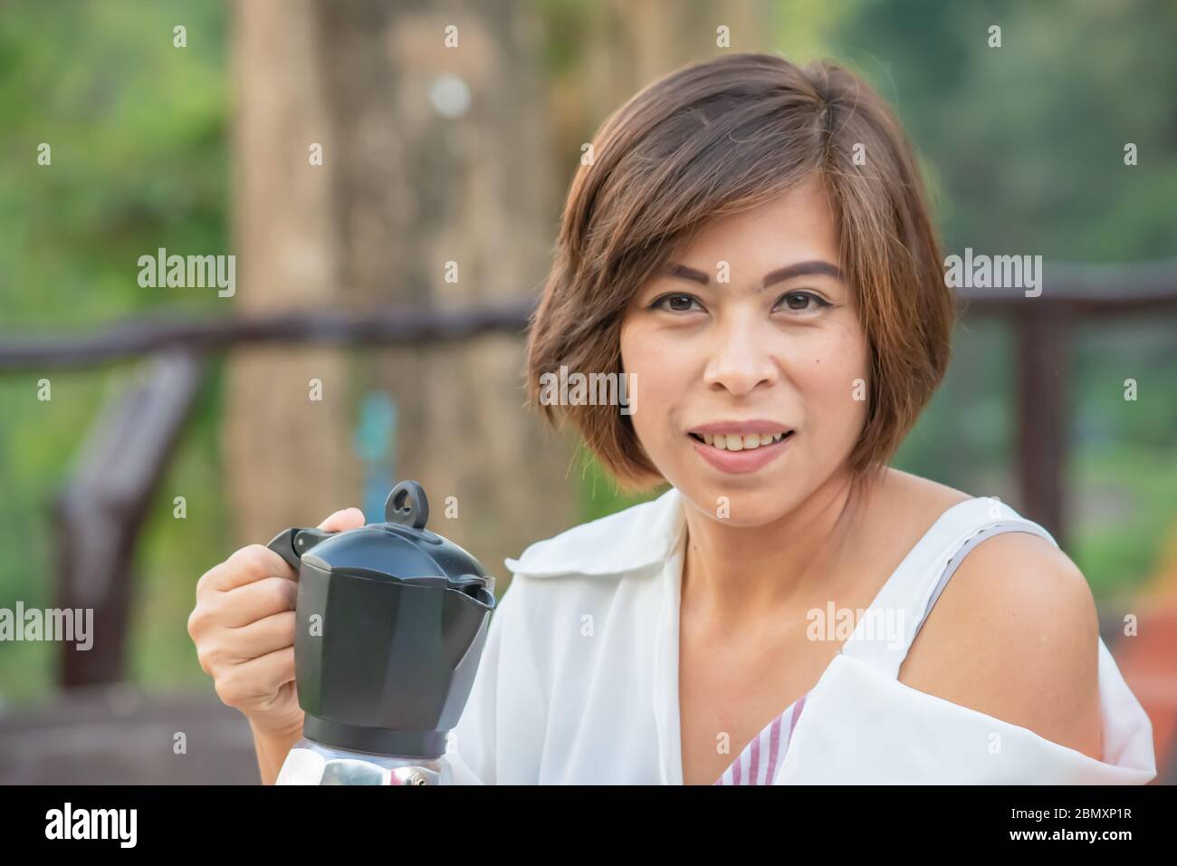 The coffee pot in the hands of Asian women. Stock Photo