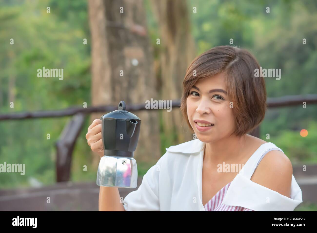 The coffee pot in the hands of Asian women. Stock Photo